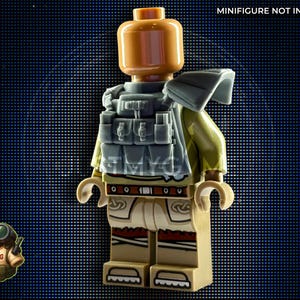 May include: A Lego minifigure with a tan head and torso, wearing a gray tactical vest and a green jacket. The minifigure has tan pants with red accents. The image also includes a small cartoon frog with the word "DUMPLING".