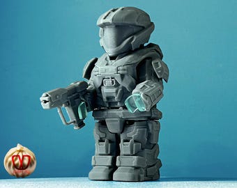 May include: A gray plastic action figure of a soldier wearing a helmet and holding a gun. The figure has a detailed design and is posed in a standing position.