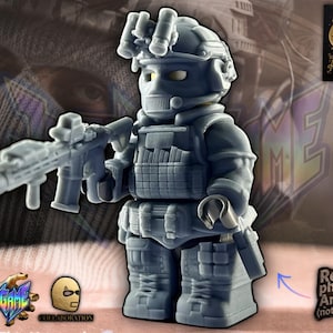 May include: A gray figurine of a soldier in tactical gear, holding a rifle. The figure has a helmet, face mask, and body armor. The background features a blurred image of a person wearing a balaclava. The text "Real physical Artwork (not a render)" is visible.