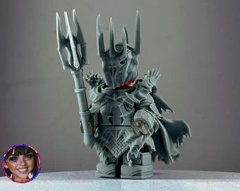 May include: A gray 3D printed figurine of a fantasy character wearing a crown and armor, holding a spear. The character has a cape and a detailed face.