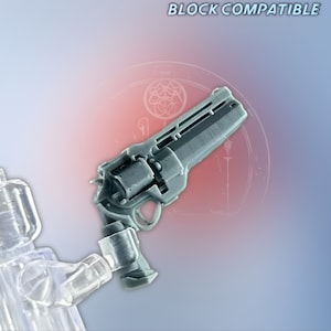 May include: A gray plastic toy gun, compatible with building blocks, with a detailed design and a textured surface. The gun is held by a clear plastic toy figure.