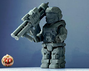 May include: A gray plastic action figure of a soldier holding a large gray plastic weapon. The soldier is wearing a helmet and armor.