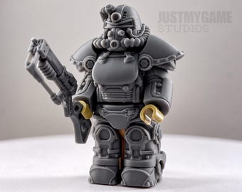 May include: A gray plastic minifigure wearing detailed power armor with a helmet, chest plate, and shoulder pauldrons. The figure holds a gray rifle in its right hand and has tan hands. The text JUSTMYGAME STUDIOS is visible in the background.