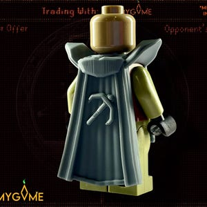 Puede incluir: Una minifigura de Lego con una capa azul con un símbolo de pico en la espalda. La minifigura está de pie sobre un fondo oscuro con el texto "Trading With" y "JustMyGame" visible.