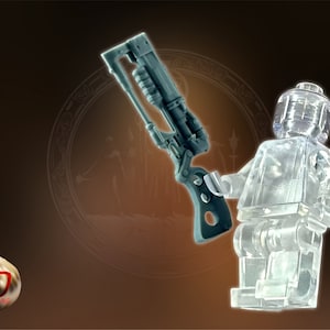 May include: A clear plastic Lego minifigure holding a dark gray and black sci-fi style weapon.