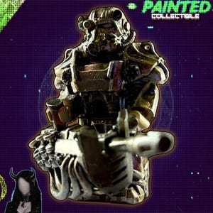 May include: A metallic painted collectible figure of a character in power armor, holding a gun. The figure is detailed with various shades of silver, bronze, and brown. The background is a gradient of purple and green with the text "PAINTED COLLECTIBLE" and "justmygyme".