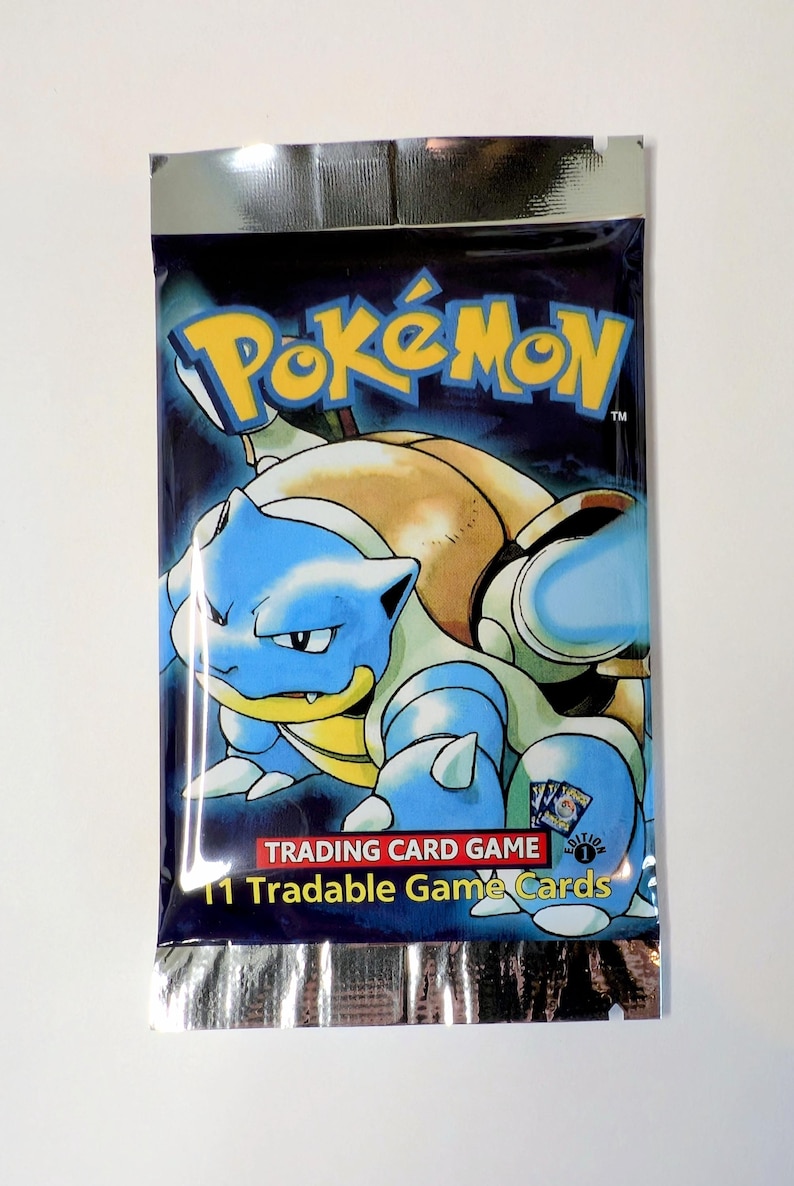 May include: Sealed Pok&eacute;mon Trading Card Game pack featuring Blastoise. The packaging is dark blue with the Pok&eacute;mon logo and a Blastoise illustration. The pack includes 11 tradable game cards.