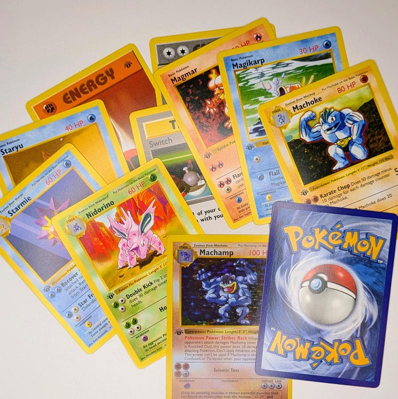 May include: A collection of Pok&eacute;mon trading cards featuring various characters and energy cards. The cards have yellow borders and feature colorful illustrations of Pok&eacute;mon like Machamp, Magikarp, and Starmie. The backs of the cards have a blue and white Pok&eacute; Ball design.