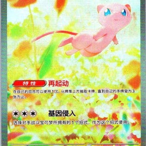 May include: A holographic Pokémon trading card featuring a pink Mew character with blue eyes and a long tail. The card has Japanese text and various symbols, including a HP value of 180. The card is a PROMO 003/SV-P.