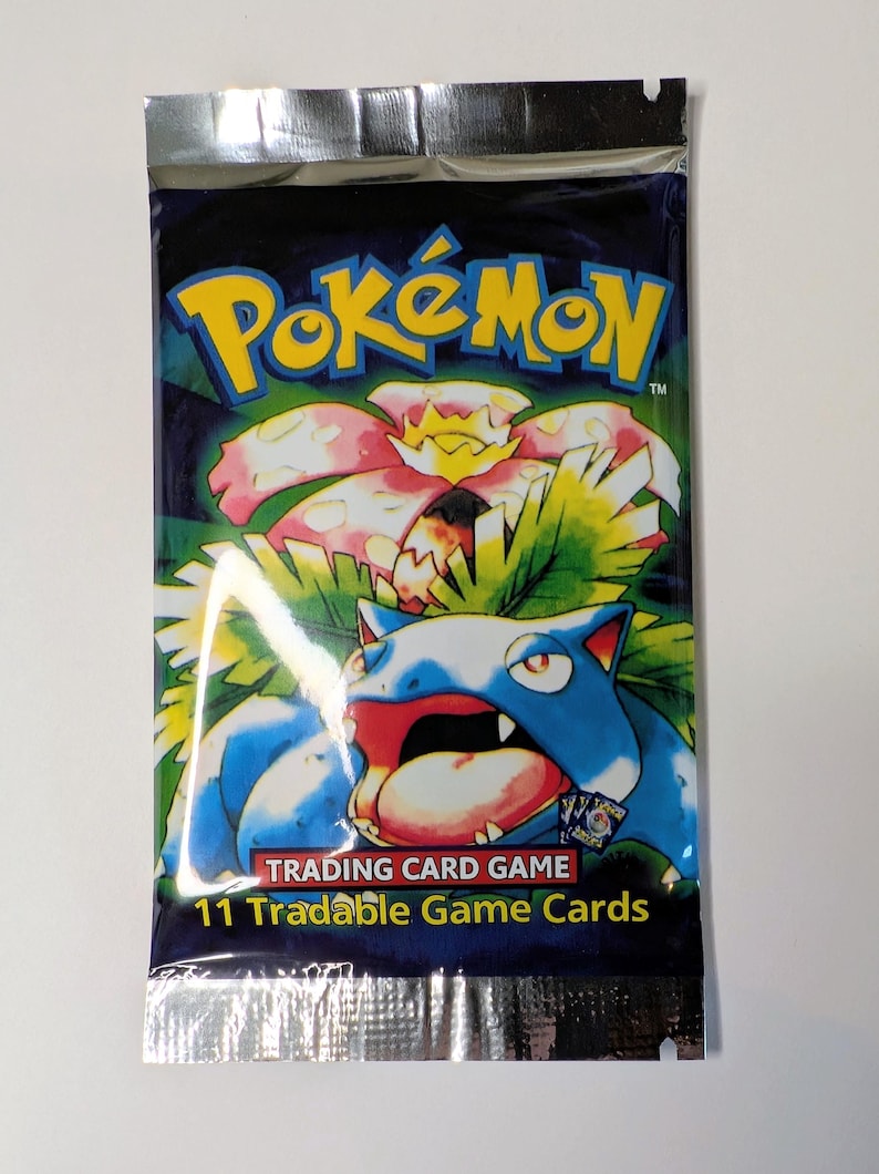 May include: Sealed Pok&eacute;mon trading card game pack. The pack features a blue and green background with the Pok&eacute;mon logo in yellow. The image on the pack shows a blue and red Pok&eacute;mon with a flower. The text reads "11 Tradable Game Cards."