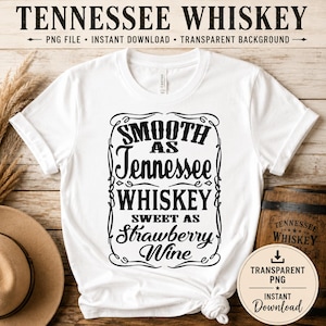 以下が含まれることがあります： 「SMOOTH as Tennessee WHISKEY & SWEET as Strawberry Wine」のテキストが装飾フレームに入った白いTシャツ。シャツの上部には「TENNESSEE WHISKEY」の文字も。木製の樽とPNGダウンロードグラフィックが見えます。