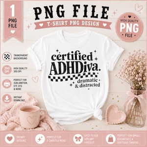 May include: White t-shirt with the text "certified ADHDiva. dramatic & distracted" in black. The design includes stars and a checkered pattern. The image also features a pink mug, a heart-shaped dish, and a vase with flowers.