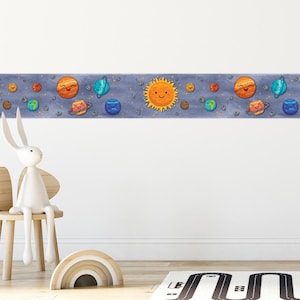 May include: A blue and white wallpaper border with a repeating pattern of planets and stars. The planets are yellow, orange, and blue with smiling faces. The stars are white and yellow.