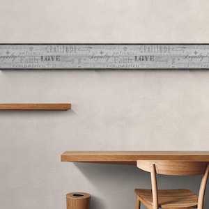 May include: A gray and white wood-look wallpaper border with the words "EMPATHY", "GRATITUDE", "LOYALTY", "FAITH", "LOVE", "FAMILY", "COMPASSION", and "DEDICATION" printed on it. The border is displayed on a white wall with a wooden desk and chair in front of it.