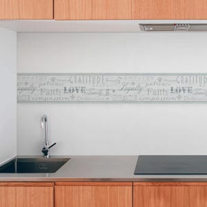 May include: A kitchen backsplash with a grey and white tiled design featuring a decorative border with the words "EMPATHY", "GRATITUDE", "LOYALTY", "LOVE", "FAITH", "GRACE", "COMPASSION", and "DEDICATION".