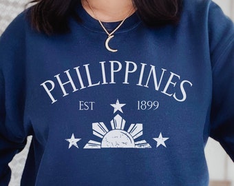 May include: Navy blue sweatshirt with a white graphic design featuring the text "PHILIPPINES EST 1899" and a stylized sun with three stars.