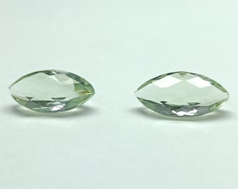 May include: Two marquise-cut gemstones with a pale green hue. The gems are faceted, reflecting light and creating a sparkling effect. The stones are set against a white background, highlighting their clarity and color. Ideal for jewelry making.