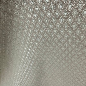 May include: Close-up of a white fabric with a subtle diamond pattern woven into the material.