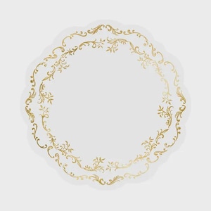 May include: A circular white paper doily featuring a scalloped edge and a decorative gold foil filigree pattern arranged in a ring. The intricate metallic gold design consists of swirling floral and vine motifs that frame the center of the doily.