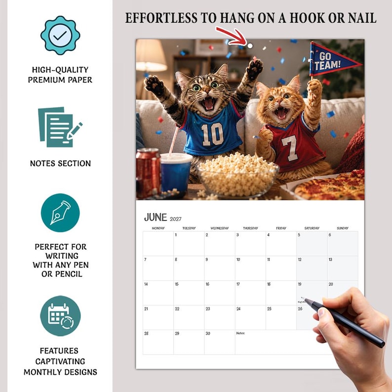 May include: A 2027 wall calendar for June featuring a photograph of two cats wearing sports jerseys, one blue with the number 10 and one red with the number 7, cheering with popcorn and pizza. The calendar includes a grid for notes and dates.