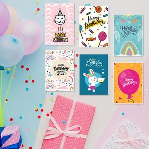 May include: Six different birthday cards with colorful designs and text. The cards feature a cat, candy, a rainbow, a bunny, and a balloon. The text on the cards says "Happy Birthday".