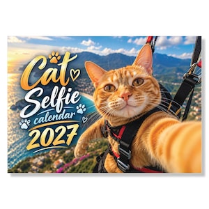 May include: A 2027 wall calendar featuring an orange tabby cat wearing a black and red harness while paragliding. The text reads Cat Selfie calendar 2027, accompanied by paw print and heart icons, set against a coastal mountain landscape background.