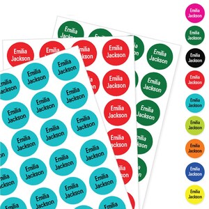 May include: Multiple sheets of circular adhesive labels in various colours including teal, red, and green. Each sticker features the name Emilia Jackson printed in a bold, sans-serif font. A vertical column displays additional colours like pink, black, and yellow.