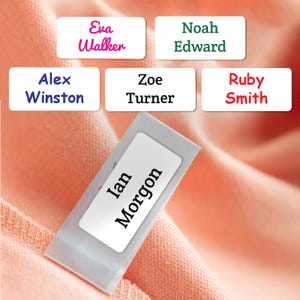May include: A collection of rectangular white clothing labels featuring various names printed in different colors and fonts, including Eva Walker, Noah Edward, Alex Winston, Zoe Turner, Ruby Smith, and Ian Morgon, displayed on a peach fabric.