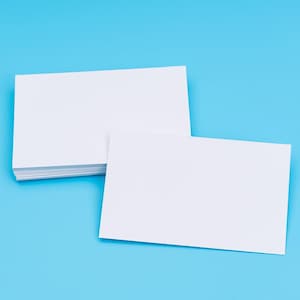May include: Two blank white cards on a light blue background. The card on the left is stacked on top of other cards. The card on the right is lying flat.