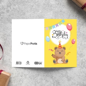 May include: A yellow birthday card with a cartoon bear wearing a party hat and holding a streamer. The card says "Happy Birthday" in a white circle with colorful flags hanging above.