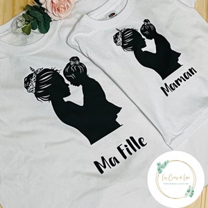 Peut inclure: Deux t-shirts blancs avec une silhouette noire d'une mère et d'un enfant. Le plus grand t-shirt dit "Ma Fille" et le plus petit dit "Maman".