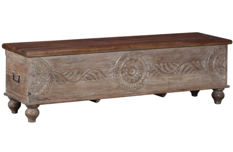 May include: A carved wooden storage chest with a light brown finish and a dark brown top. The chest has intricate floral designs and sits on four turned legs.