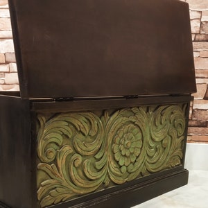 May include: A wooden storage chest with a hinged lid. The chest is painted black with a green floral design carved into the front.
