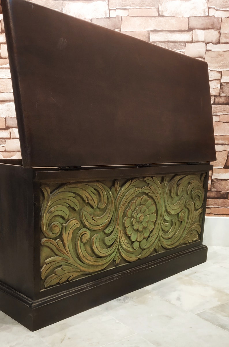 May include: A wooden storage chest with a hinged lid. The chest is painted black with a green floral design carved into the front.