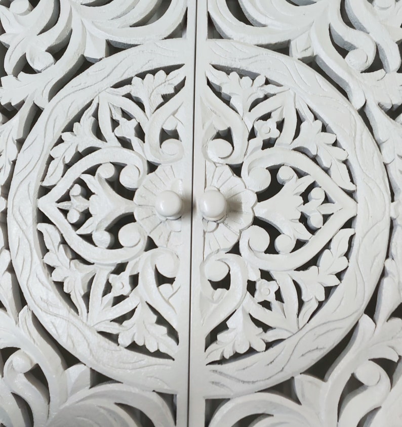 May include: White wooden cabinet doors with intricate carved floral designs and round knobs.