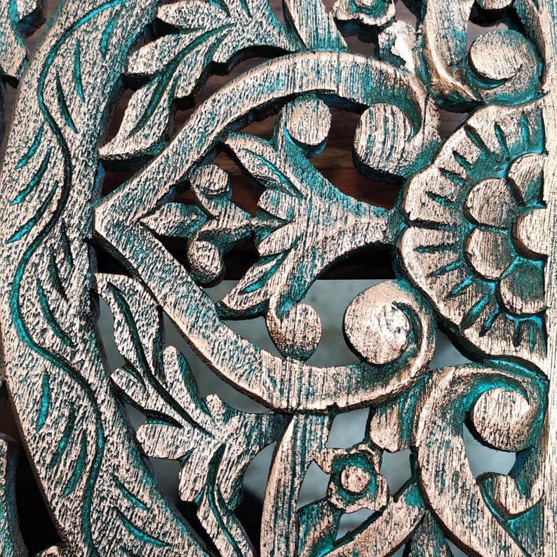 May include: Intricate carved wooden design with a teal and copper finish. The design features floral and leaf motifs.