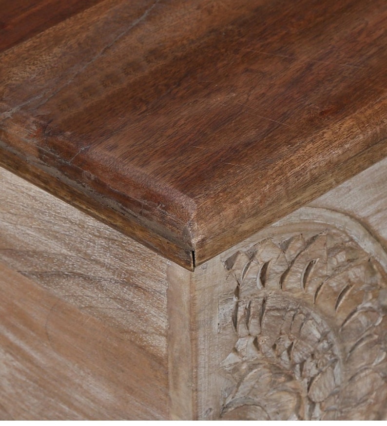 May include: A wooden storage box with a carved design on the front. The top of the box is a darker wood and has a smooth finish.