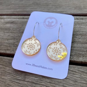 May include: Gold snowflake ornament earrings with a white snowflake design. The earrings are on a white card with the text "3 Bears Makes" and "www.3BearsMakes.com".