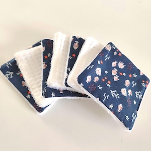 Peut inclure: Ensemble de six carrés réutilisables pour le visage. Les carrés présentent un tissu bleu marine avec un motif blanc et corail, associé à un tissu blanc texturé. Les bords sont finis avec une bordure blanche.