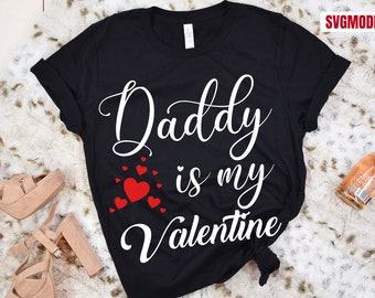 May include: Black t-shirt with white text that reads "Daddy is my Valentine" and red heart graphics.