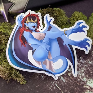 May include: A sticker featuring a blue gargoyle woman with red hair, gold jewelry, and dark purple wings. The illustration has a cartoon style and is set against a background of green moss and a sword.