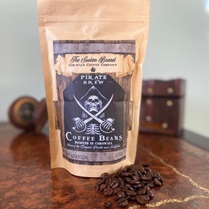 Może przedstawiać: Brązowy papierowy worek z etykietą w stylu pirackim. Etykieta przedstawia czaszkę i skrzyżowane kości z tekstem "Pirate Brew Coffee Beans" i "Roasted in Cornwall".