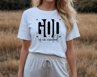 May include: White t-shirt with black text that reads "GOD is in control" with a black and white speckled design.