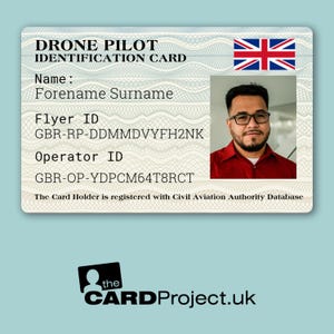 May include: A white card with a blue and red Union Jack flag in the top right corner. The card reads "DRONE PILOT IDENTIFICATION CARD" and includes the text "Name: Forename Surname", "Flyer ID: GBR-RP-DDMMDVYFH2NK", "Operator ID: GBR-OP-YDPCM64T8RCT", and "The Card Holder is registered with Civil Aviation Authority Database". A man with a beard and glasses is pictured in the top right corner.
