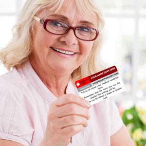 May include: A white medical alert card with red accents. The card has the text "YOUR NAME GOES HERE" and "YOUR CONDITION GOES HERE". The text on the card reads: "Tell us all about your medical condition here. Remember that the more you say, the smaller the writing will be. It can be either a single or double card."