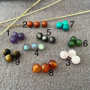 Puede incluir: Una colecci&oacute;n de cuentas de piedras preciosas en varios colores y tipos. Las cuentas incluyen amatista, jaspe rojo, turquesa, jade, cuarzo rosa, labradorita, piedra dorada, cornalina y ojo de tigre. Las cuentas son redondas y pulidas, con una superficie lisa.
