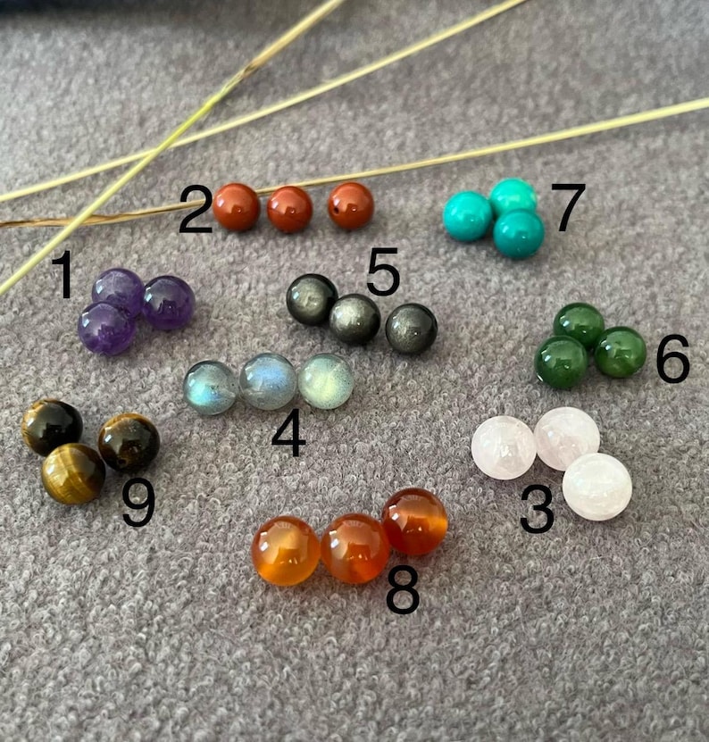 Puede incluir: Una colecci&oacute;n de cuentas de piedras preciosas en varios colores y tipos. Las cuentas incluyen amatista, jaspe rojo, turquesa, jade, cuarzo rosa, labradorita, piedra dorada, cornalina y ojo de tigre. Las cuentas son redondas y pulidas, con una superficie lisa.
