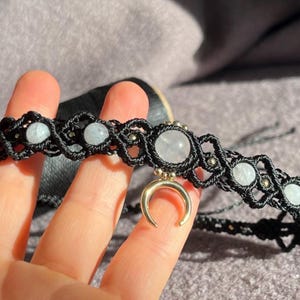 Puede incluir: Collar gargantilla de macram&eacute; negro con piedras preciosas azul claro y blancas y un dije de media luna dorada. El collar presenta un dise&ntilde;o tejido con peque&ntilde;as cuentas met&aacute;licas, creando una est&eacute;tica bohemia.
