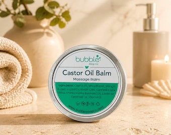 May include: A round silver metal tin of Bubble Soap Co Castor Oil Balm massage balm. The white label features teal text, a green section listing ingredients including castor oil, shea butter, and mango butter, and the website www.bubblesoapco.com.