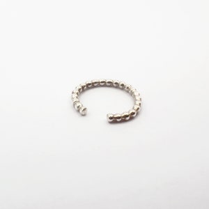 Op de afbeelding: Een zilveren ring gemaakt van kleine, ronde kralen.